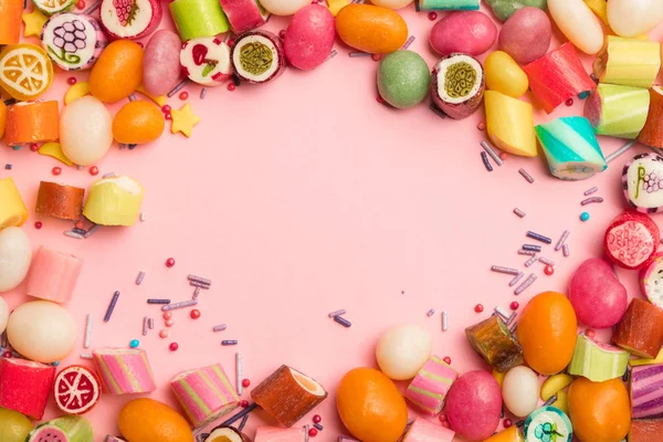 Vista dall'alto di deliziose caramelle multicolori e spruzzi su sfondo rosa — Foto stock