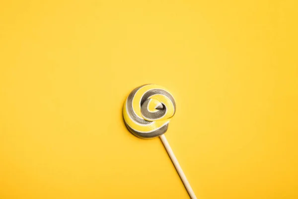 Top view of delicious multicolored swirl lollipop on wooden stick on yellow background — Stock Photo