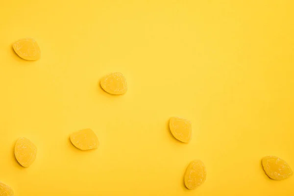 Vista superior de deliciosas jaleas azucaradas esparcidas sobre fondo amarillo - foto de stock