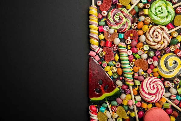 Vista superior de deliciosos doces multicoloridos no fundo preto com espaço de cópia — Fotografia de Stock