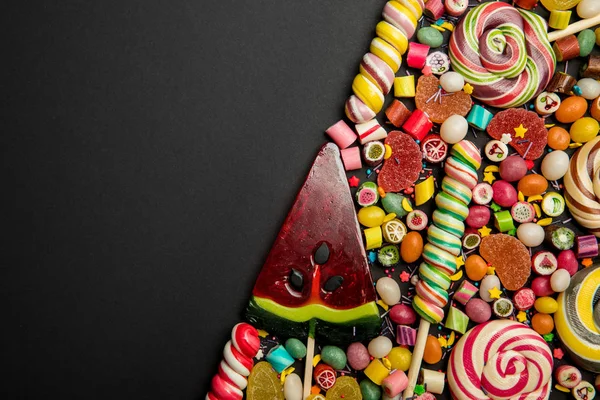 Top view of delicious multicolored sweets on black background with copy space — Stock Photo