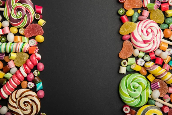 Вид зверху смачні різнокольорові цукерки на чорному тлі з місцем для тексту — стокове фото