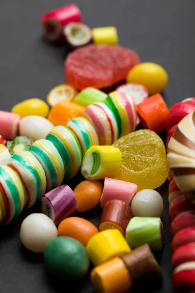 Selective focus of delicious multicolored caramel and jelly candies on black background — Stock Photo