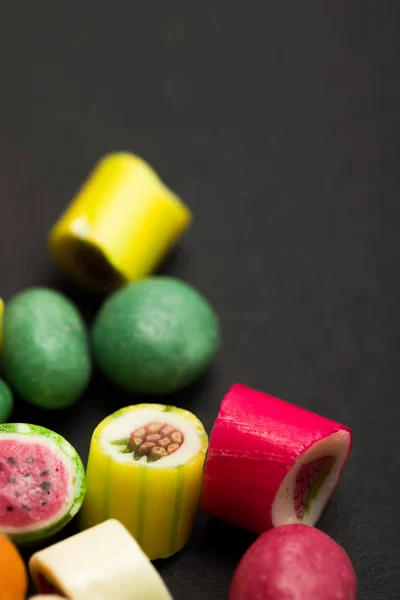 Enfoque selectivo de deliciosos caramelos de frutas multicolores sobre fondo negro - foto de stock