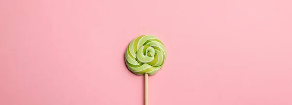 Panoramic shot of green round lollipop on wooden stick on pink background — Stock Photo