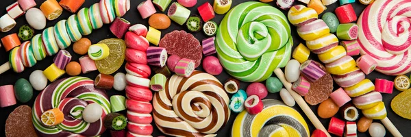Panoramic shot of bright round and swirl lollipops among fruit caramel candies — Stock Photo