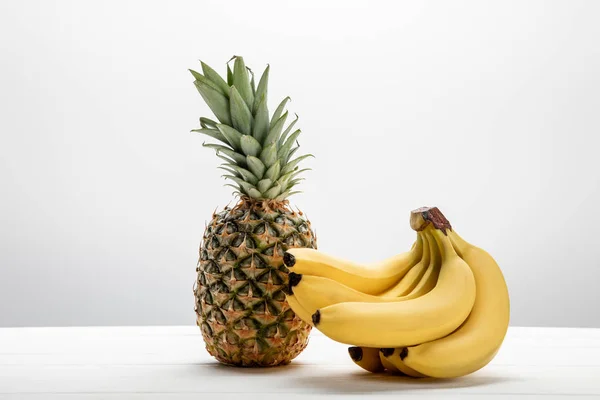 Reife gelbe Bananen in der Nähe von süßen und schmackhaften Ananas auf weißer — Stockfoto