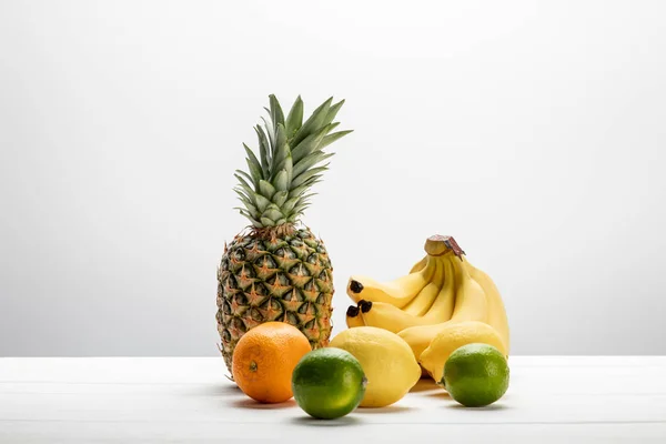 Bananas amarelas perto de abacaxi maduro, limões, laranja e limas em branco — Fotografia de Stock