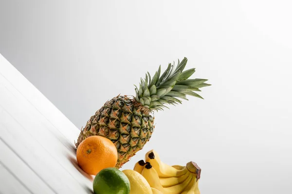 Ripe pineapple, lemon, orange and lime near bananas on white — Stock Photo