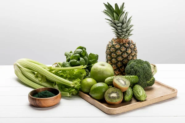 Abacaxi saboroso, maçã e limas perto de verduras orgânicas e cruas no branco — Fotografia de Stock