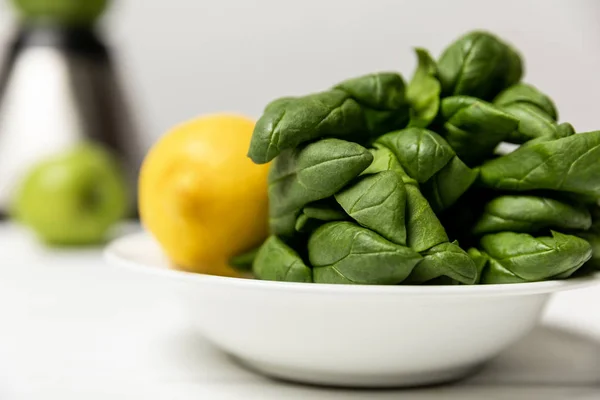 Foyer sélectif des feuilles d'épinards frais verts près du citron jaune sur blanc — Photo de stock