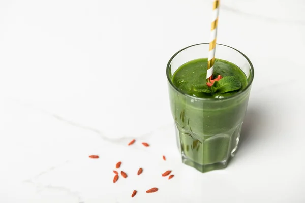 Selective focus of tasty smoothie with goji berries and mint in glass with straw on white — Stock Photo