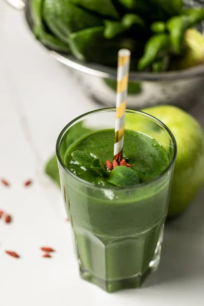 Selective focus of tasty smoothie in glass with straw near spinach leaves and apple on white — Stock Photo