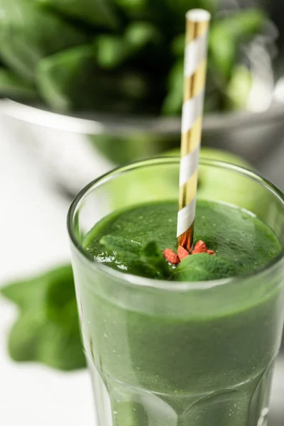 Selektiver Fokus von schmackhaftem grünem Smoothie im Glas mit Stroh in der Nähe von Spinatblättern auf Weiß — Stockfoto