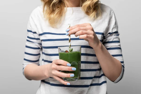 Cropped view of woman holding straw and glass with tasty green smoothie on white — Stock Photo