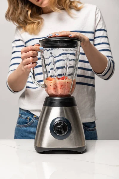 Cropped view of woman preparing tasty smoothie in blender on white — Stock Photo