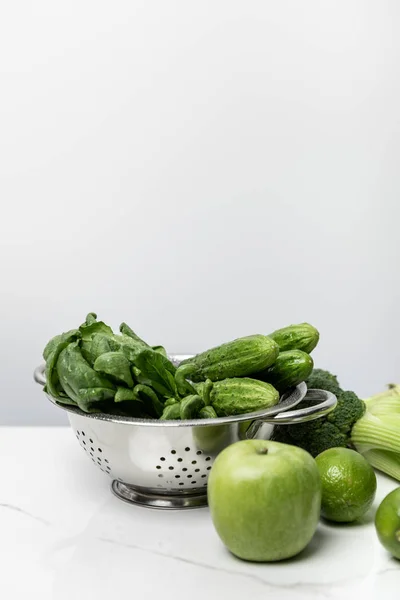 Manzana verde cerca de verduras sabrosas y hojas de espinaca en blanco - foto de stock