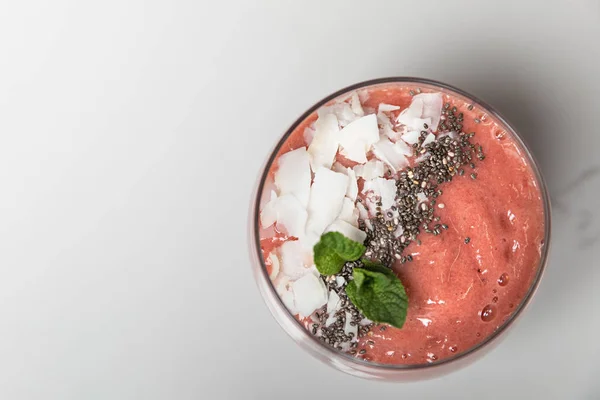 Top view of tasty pink smoothie with coconut flakes in glass on grey — Stock Photo