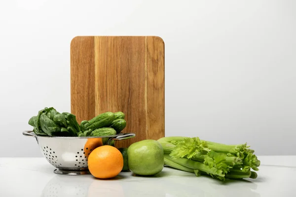Fruits savoureux et sucrés près de la maturité, légumes frais et planche à découper en bois sur gris — Photo de stock
