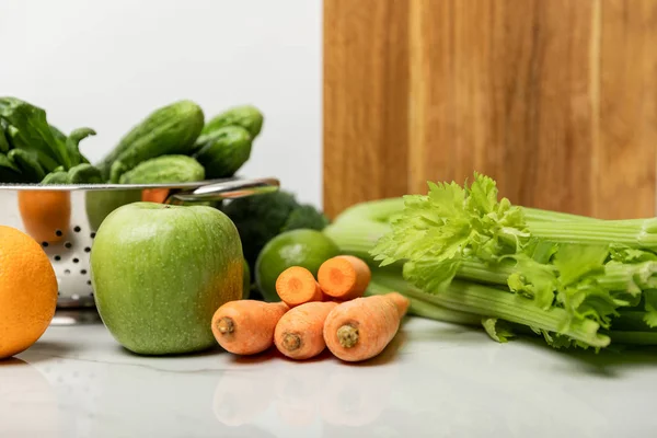 Вкусные фрукты около спелых, свежие овощи и деревянная доска для резки на белом — стоковое фото
