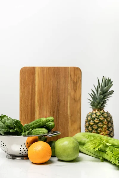 Fruits mûrs près de légumes frais et planche à découper en bois sur blanc — Photo de stock