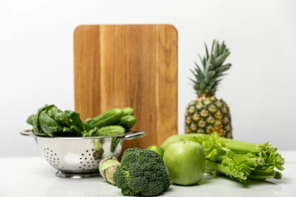 Selective focus of broccoli near ripe fruits and fresh green vegetables on white — Stock Photo