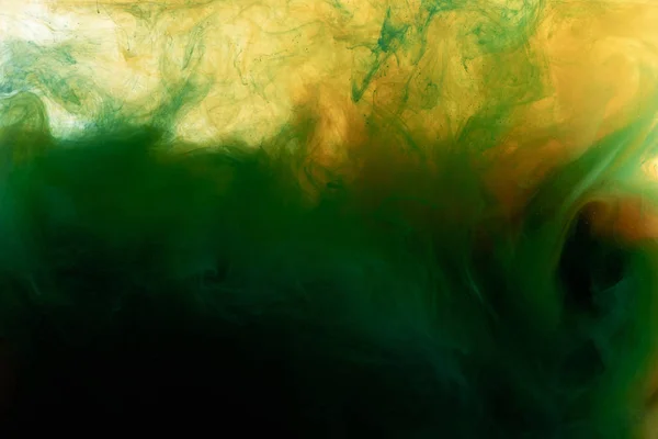 Vista de cerca de la mezcla de pintura verde oscuro y naranja en agua - foto de stock