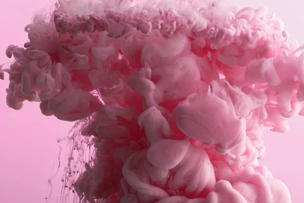 Vista de cerca de salpicaduras de pintura rosa en agua aislada en rosa - foto de stock