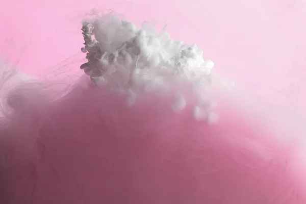 Close up view of white and pink paint mixing in water isolated on pink — Stock Photo