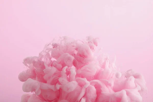 Close up view of pink paint swirls in water isolated on pink — Stock Photo