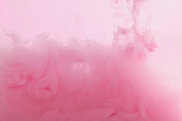 Vista de cerca de la mezcla de pintura rosa en agua - foto de stock