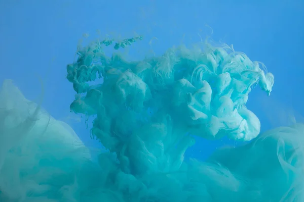 Vista de perto dos redemoinhos de tinta turquesa isolados em azul — Fotografia de Stock