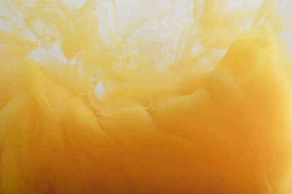 Vista de cerca de la pintura naranja clara mezclando en agua - foto de stock