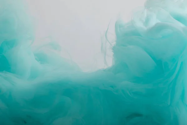 Крупный план вихрей бирюзовой краски, изолированных на сером — стоковое фото