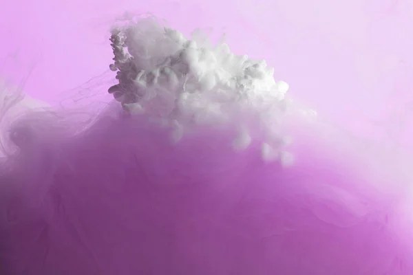 Vista de cerca de la mezcla de pintura rosa y blanca en agua aislada en rosa - foto de stock