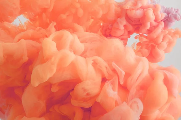 Vue rapprochée de la peinture corail tourbillonne dans l'eau — Photo de stock