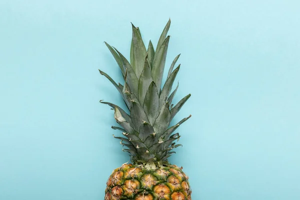 Top view of whole ripe tropical pineapple with green leaves on blue background with copy space — Stock Photo