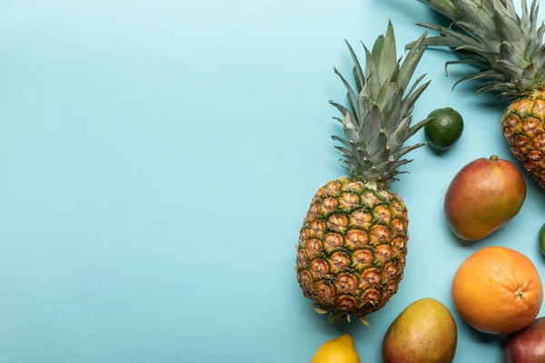 Top view of ripe exotic fresh fruits on blue background with copy space — Stock Photo