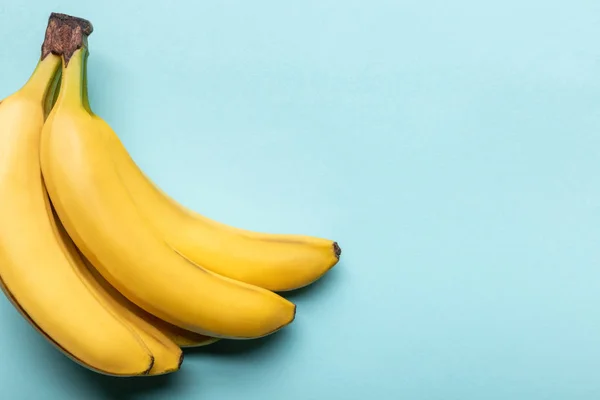 Верхний вид спелых желтых бананов на синем фоне с копировальным пространством — стоковое фото