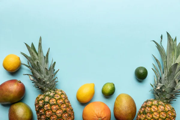 Draufsicht auf ganze reife tropische Früchte auf blauem Hintergrund — Stockfoto