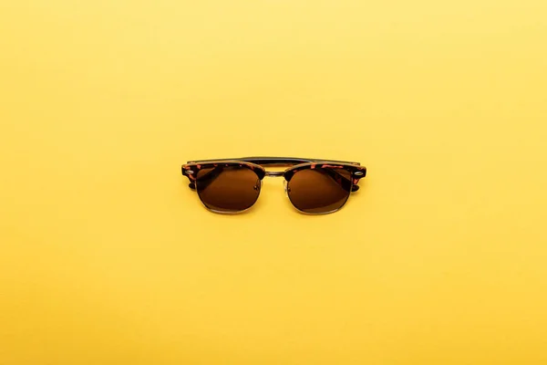 Vue de dessus des lunettes de soleil tendance sur fond jaune — Photo de stock