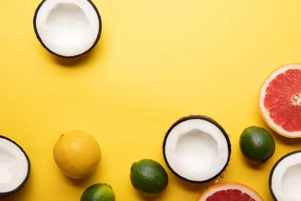 Top view of citrus fruits and coconuts on yellow background with copy space — Stock Photo