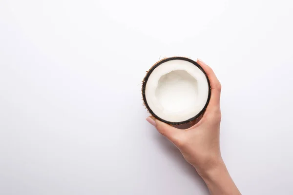 Cropped view of woman holding ripe coconut half on white background with copy space — Stock Photo