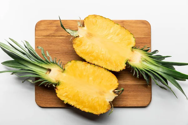 Top view of cut ripe yellow pineapple on wooden chopping board on white background — Stock Photo