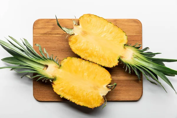 Vue du dessus de l'ananas jaune mûr coupé sur planche à découper en bois sur fond blanc — Photo de stock