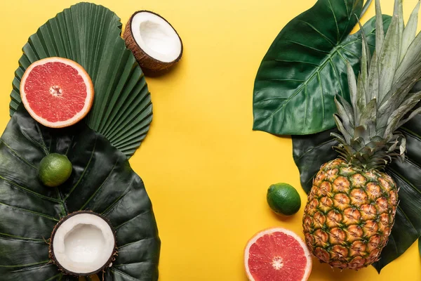 Vista superior de frutas exóticas orgánicas maduras sobre fondo amarillo con hojas verdes - foto de stock