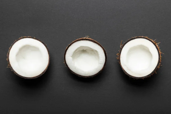 Вид зверху на половинки кокосового горіха на чорному тлі — стокове фото