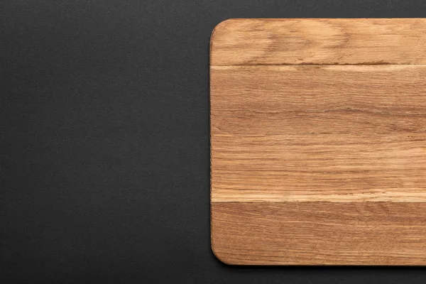 Top view of empty wooden cutting board on black background — Stock Photo