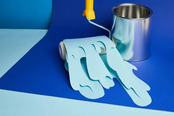 Metal shiny can and roller with dripping paper cut paint on bright blue background — Stock Photo