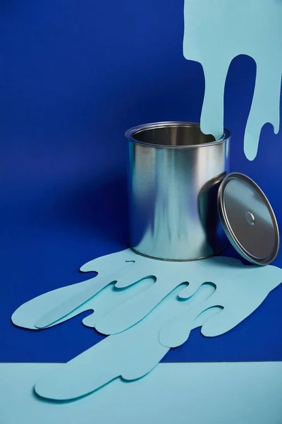 Can and dripping paper cut paint on bright blue background — Stock Photo